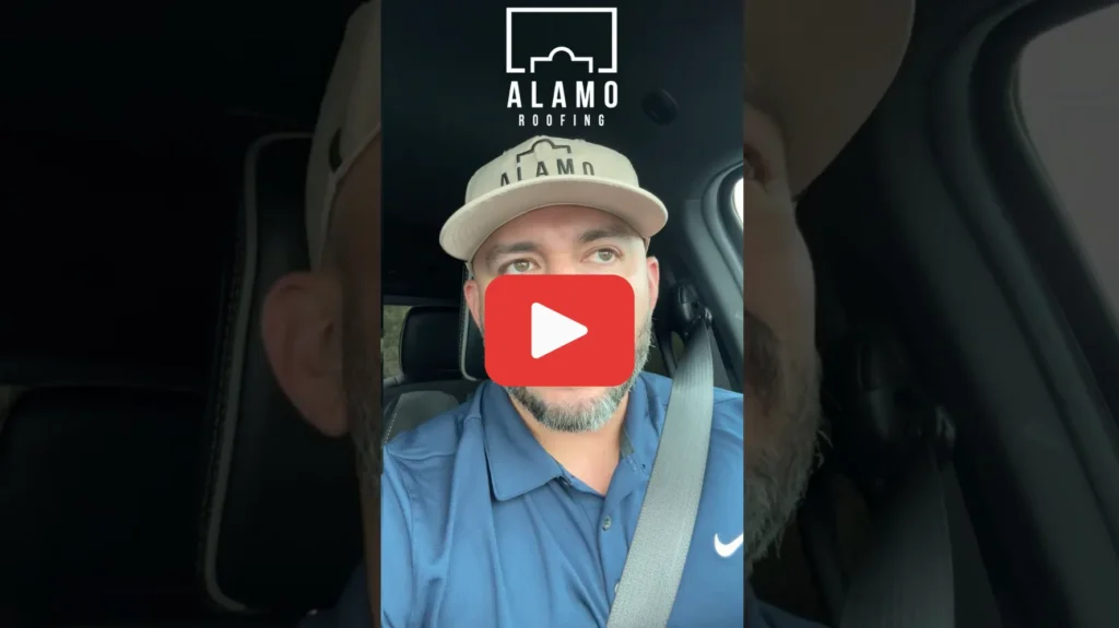 A man wearing an ALAMO cap and a blue polo shirt sits in a car, looking at the camera. The Alamo Roofing logo is at the top of the image, and a large play button is centered.